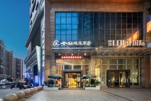 A hotel entrance with a modern facade, large glass windows, and a prominent sign.