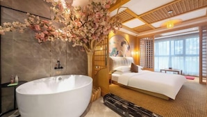 A modern hotel room with a large bathtub, a bed, and a decorative tree. - KINCO Hotel (Huizhou Huiyang Station) (Huizhou)