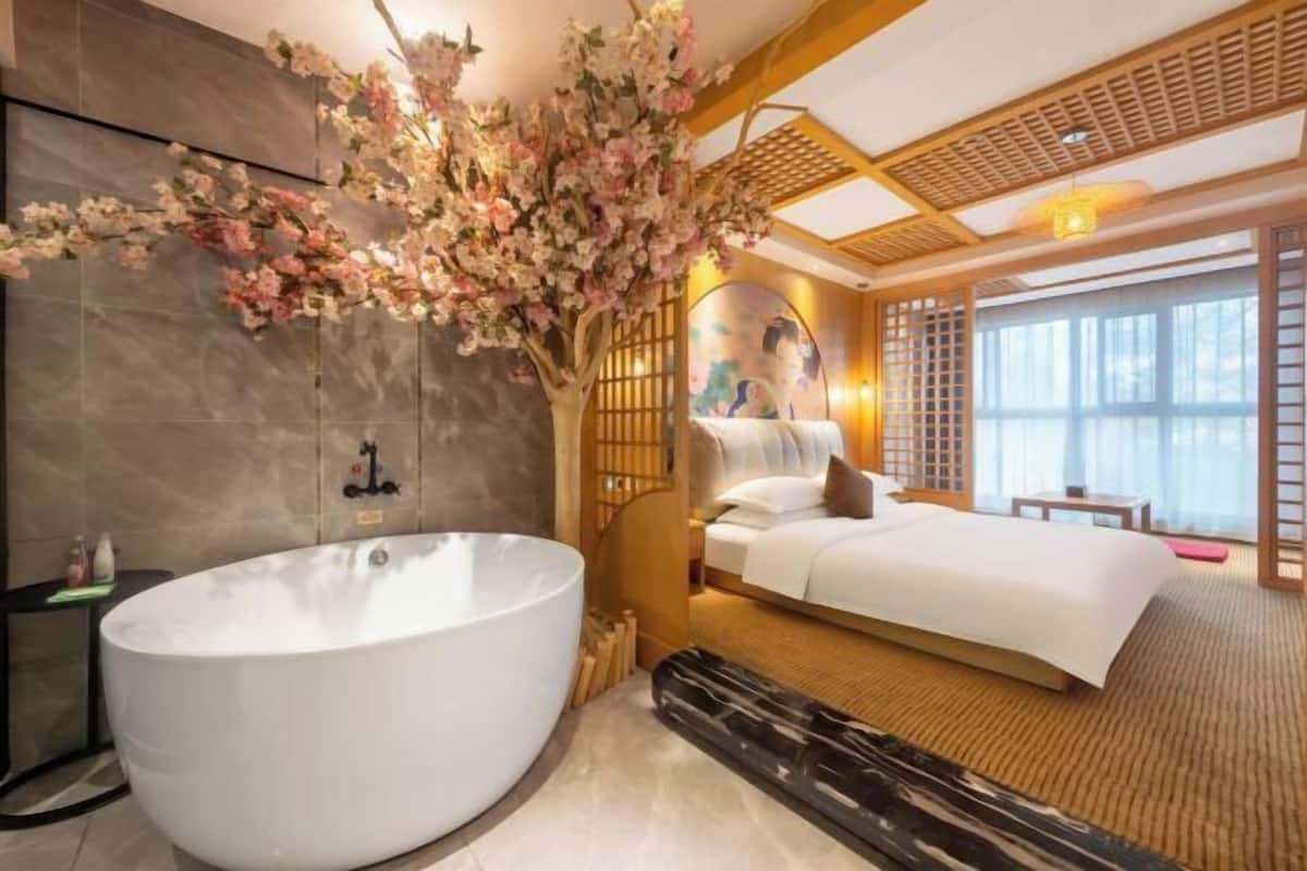 Ein modernes Hotelzimmer mit einer großen Badewanne, einem Bett und einem Zierbaum.