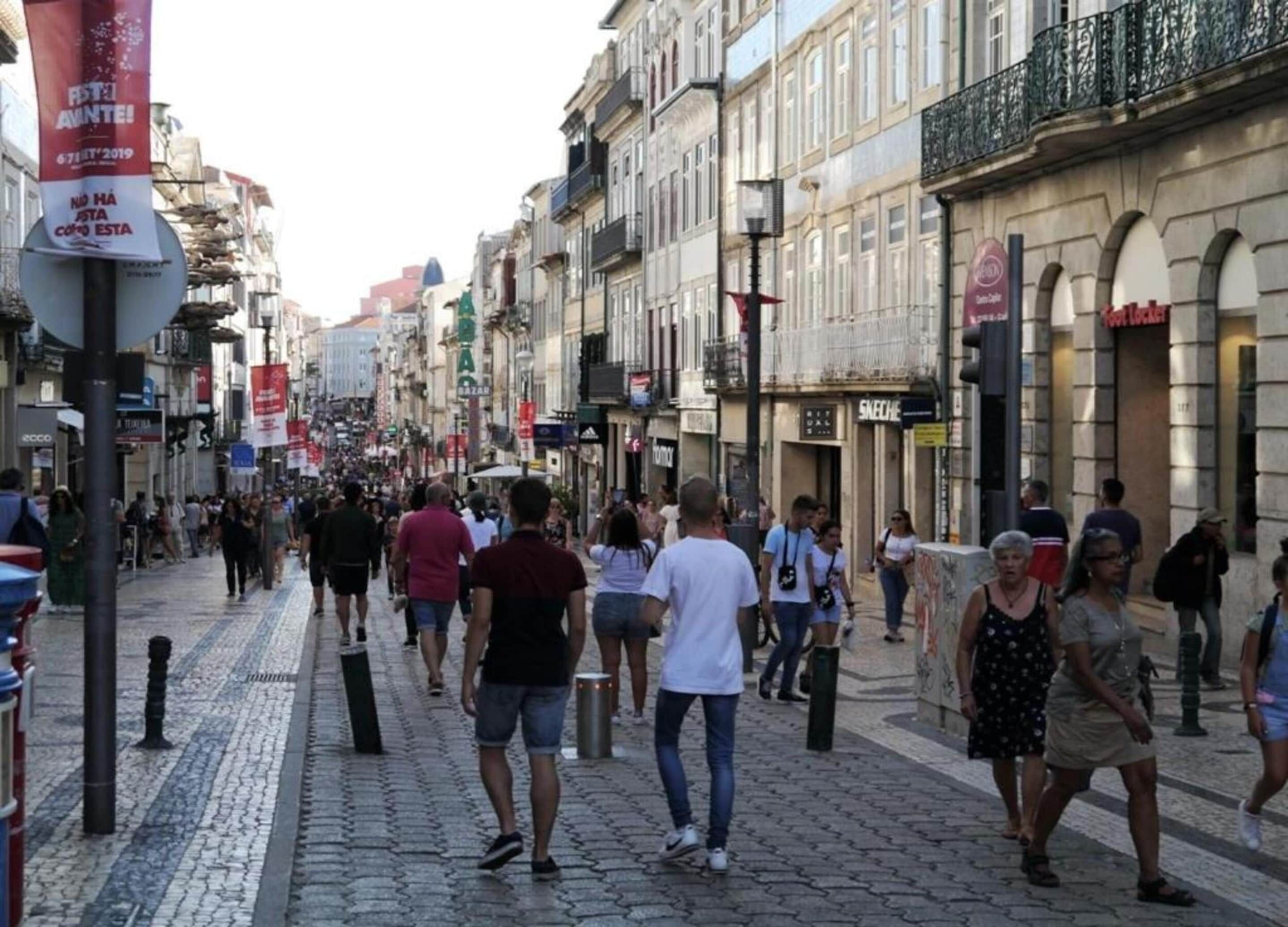 Una calle urbana concurrida, con peatones, comercios y edificios históricos.