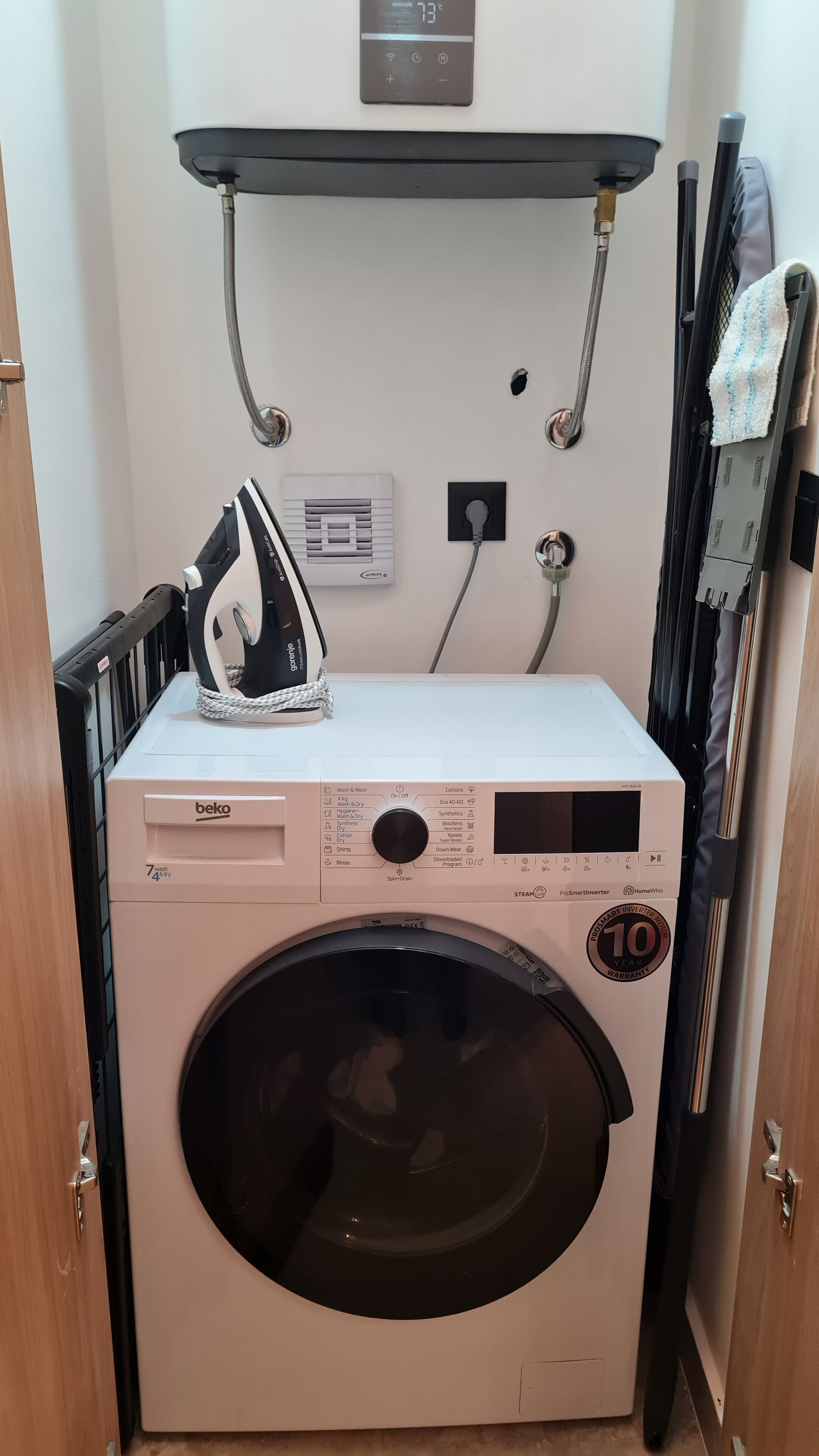 A compact washing machine with a 10-year warranty, a control panel, and a small iron on top.