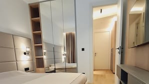 A modern bedroom with a large bed, built-in wardrobe, and a TV. - Air Onia (Budva)