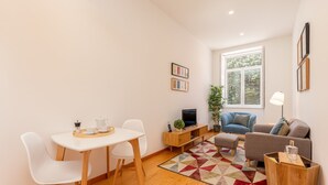 A modern living room with a dining table, sofa, and TV stand. - Charming 1-bedroom Apartment in Oporto (Porto)