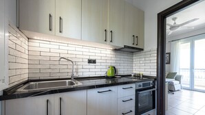 A modern kitchen with white cabinets, a stainless steel sink, and a built-in oven.