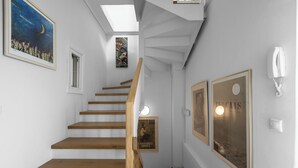 A staircase with wooden steps, a skylight, and framed artwork on the walls.