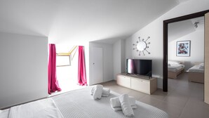 A modern bedroom with a large bed, a TV on a cabinet, and a skylight with curtains.