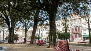A park with benches, trees, and buildings in the background. - Cozy 2-bedroom Apartment in Porto (Porto)