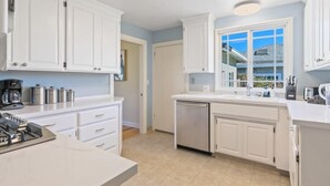 A modern kitchen with white cabinets, a dishwasher, and a coffee maker. - @ Marbella Lane - Modern and Sleek Home in Redwood (Redwood City)