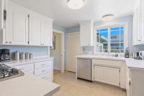 A modern kitchen with white cabinets, a dishwasher, and a coffee maker.