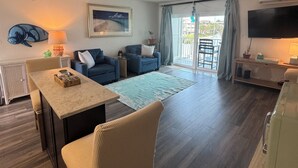 Ein Wohnzimmer mit Essbereich, Fernseher und Blick ins Freie.