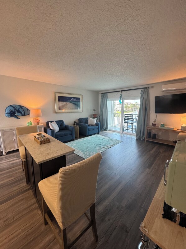 A living room with a dining area, a TV, and a view to the outside.