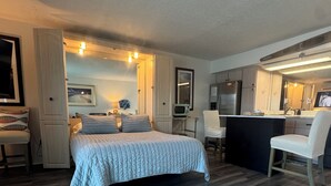 Ein Schlafzimmer mit Bett, Schreibtisch, Stuhl und einer Küchenzeile.