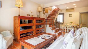 A cozy living room with a wooden cabinet, a staircase, and a dining area.