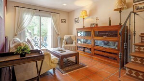 A cozy living room with a sofa, armchair, and a wooden cabinet with glass doors.