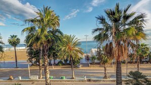Una carretera costera bordeada de palmeras, con una playa al fondo.