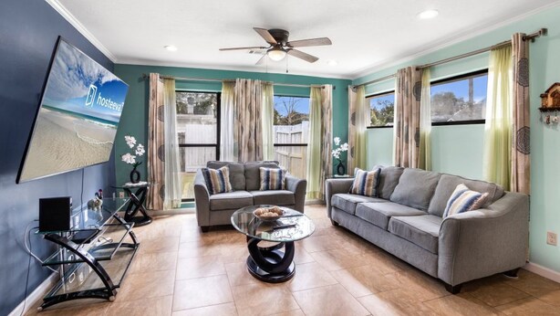 A living room with two grey sofas, a glass coffee table, and a ceiling fan. - Wellington 4BR House (Fort Walton Beach)