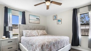 A bedroom with a bed, a nightstand, a ceiling fan, and a window with curtains. - Wellington 4BR House (Fort Walton Beach)