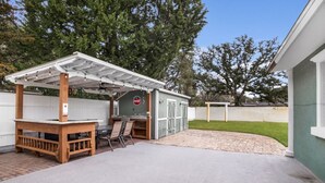 A covered patio area with a wooden table and chairs, a small shed, and a fenced yard. - Wellington 4BR House (Fort Walton Beach)