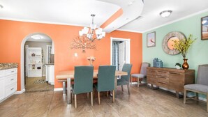 A dining area with a wooden table and chairs, a chandelier, and a buffet cabinet. - Wellington 4BR House (Fort Walton Beach)
