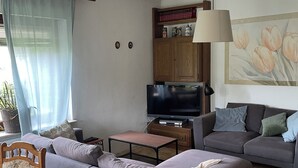 Una sala de estar con dos sofás, una mesa de centro, un televisor y una estantería.