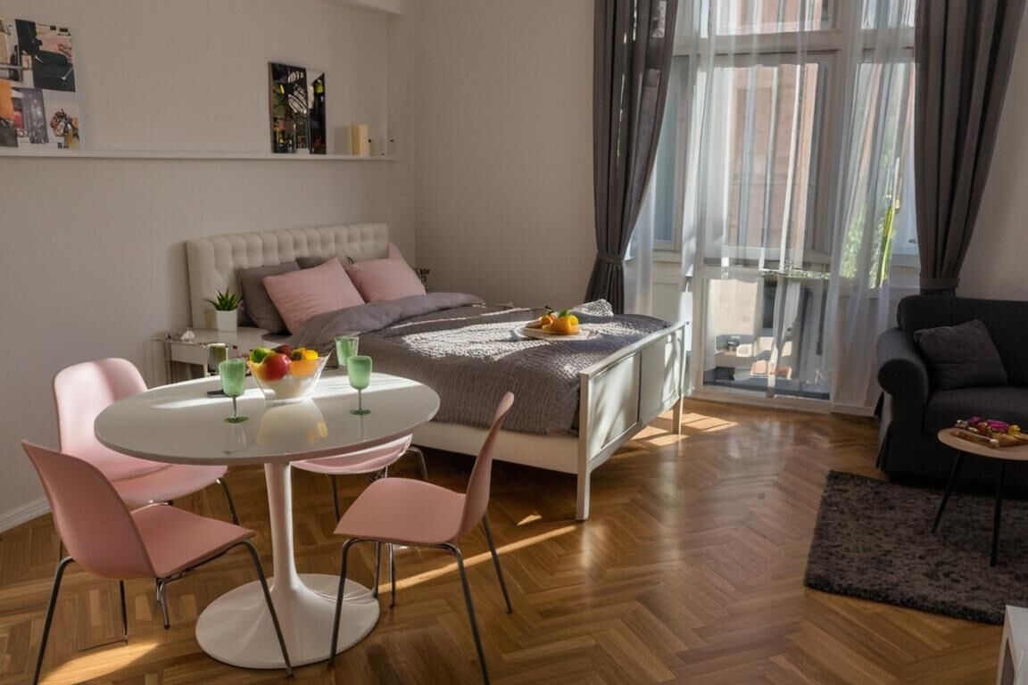 A modern bedroom with a bed, bedside table, and a dining area with chairs and a table.