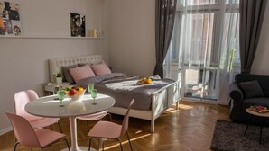 Een moderne slaapkamer met een bed, nachtkastje en een eethoek met stoelen en een tafel.