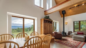A spacious living area with a large wooden dining table, comfortable seating, and a view of the outdoors.