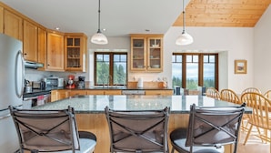 A modern kitchen with wooden cabinets, a granite countertop, and a central island with bar stools.