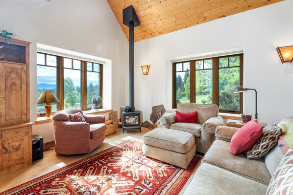 Una sala de estar acogedora con chimenea, ventanas amplias y un mobiliario cómodo.