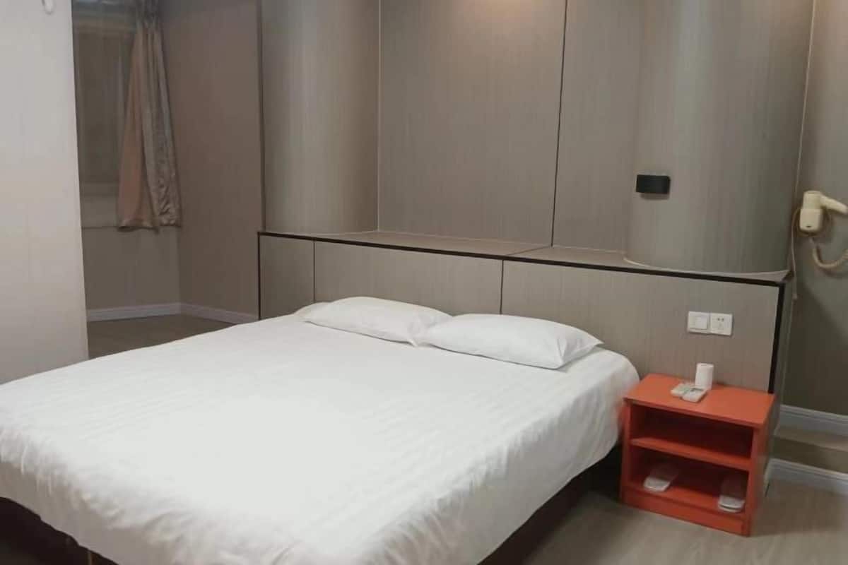 A hotel room with a bed, a nightstand, and a wall-mounted telephone.