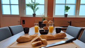 Ein Frühstücksarrangement mit Brot, Saft und einem Messer auf einer Holzbrett.