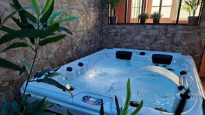 Ein Whirlpool mit Bedienfeld, umgeben von Steinmauern und Topfpflanzen.