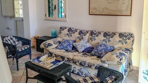 A living room with a floral sofa, two armchairs, a coffee table, and a framed map on the wall. - Villa Le Cicale - Salento (Morciano di Leuca)