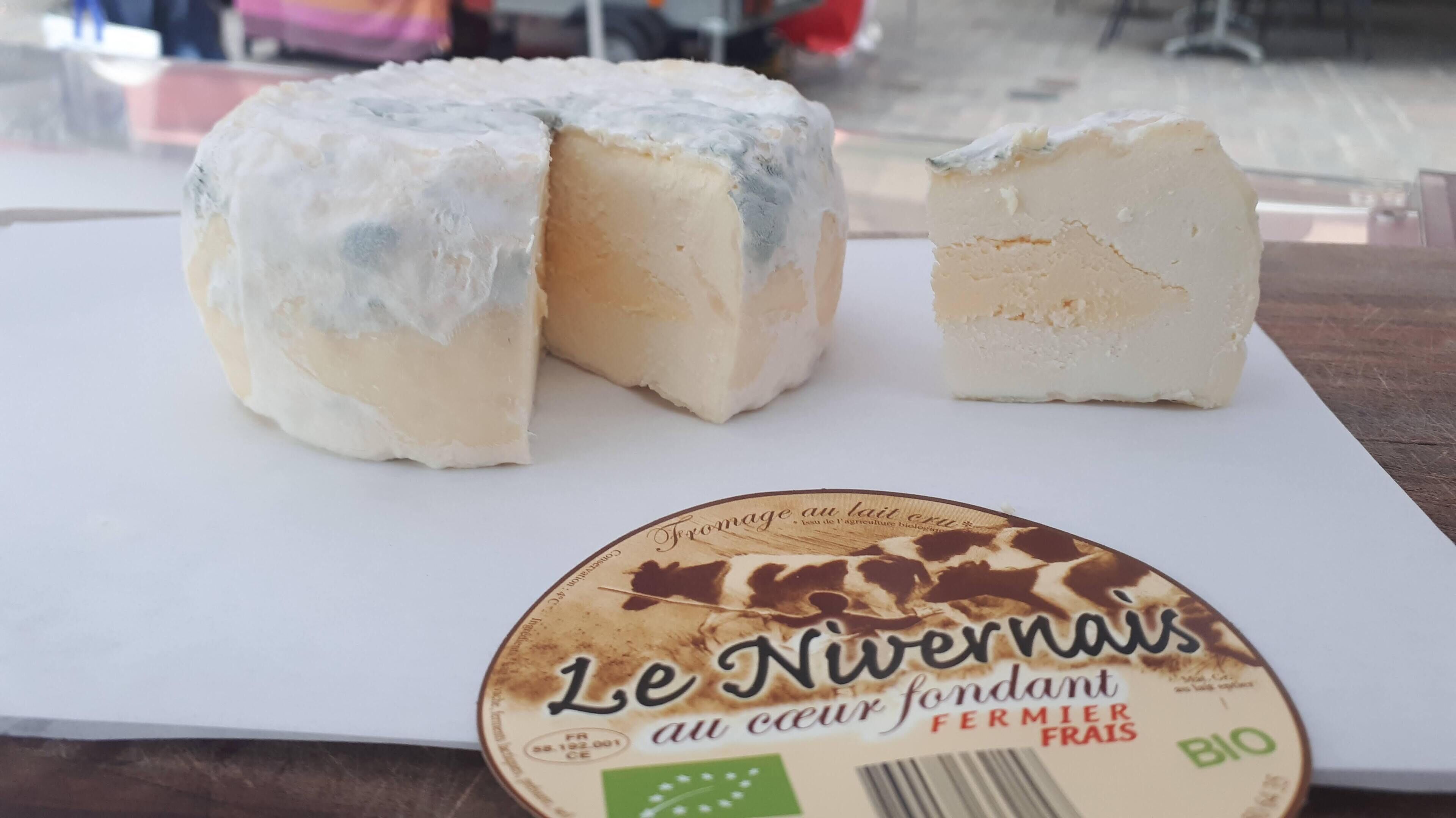 Un queso Le Nivernais sobre un plato blanco con una etiqueta.