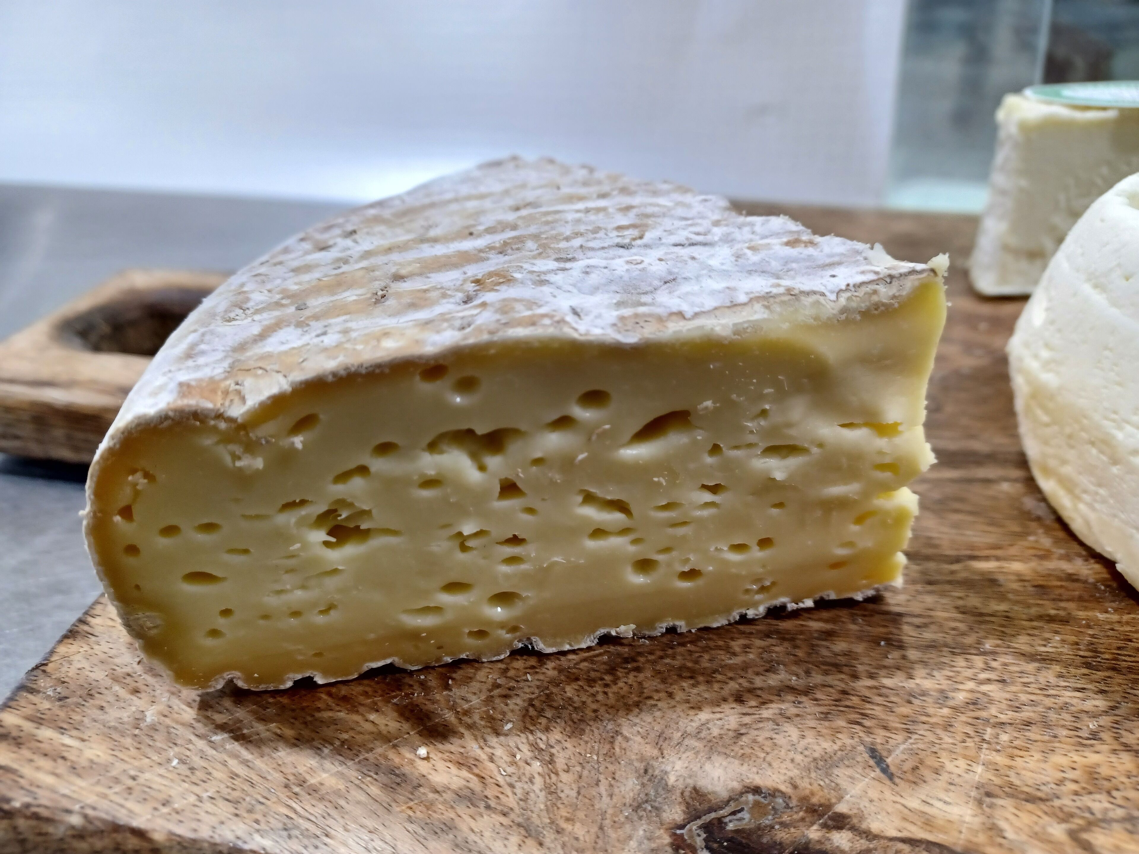 A wedge of cheese on a wooden cutting board.