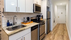 Cocina compacta con alacenas blancas, pileta de acero inoxidable, horno empotrado y microondas.