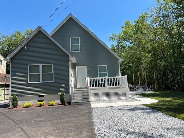 A two-story house with a front porch and a gravel driveway. - Beach House By The Bay, 9 Car Parking, Linen Included (Lower Township)