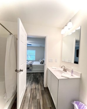 An en-suite bathroom with a white vanity, a mirror, and a shower curtain. - Beach House By The Bay, 9 Car Parking, Linen Included (Lower Township)