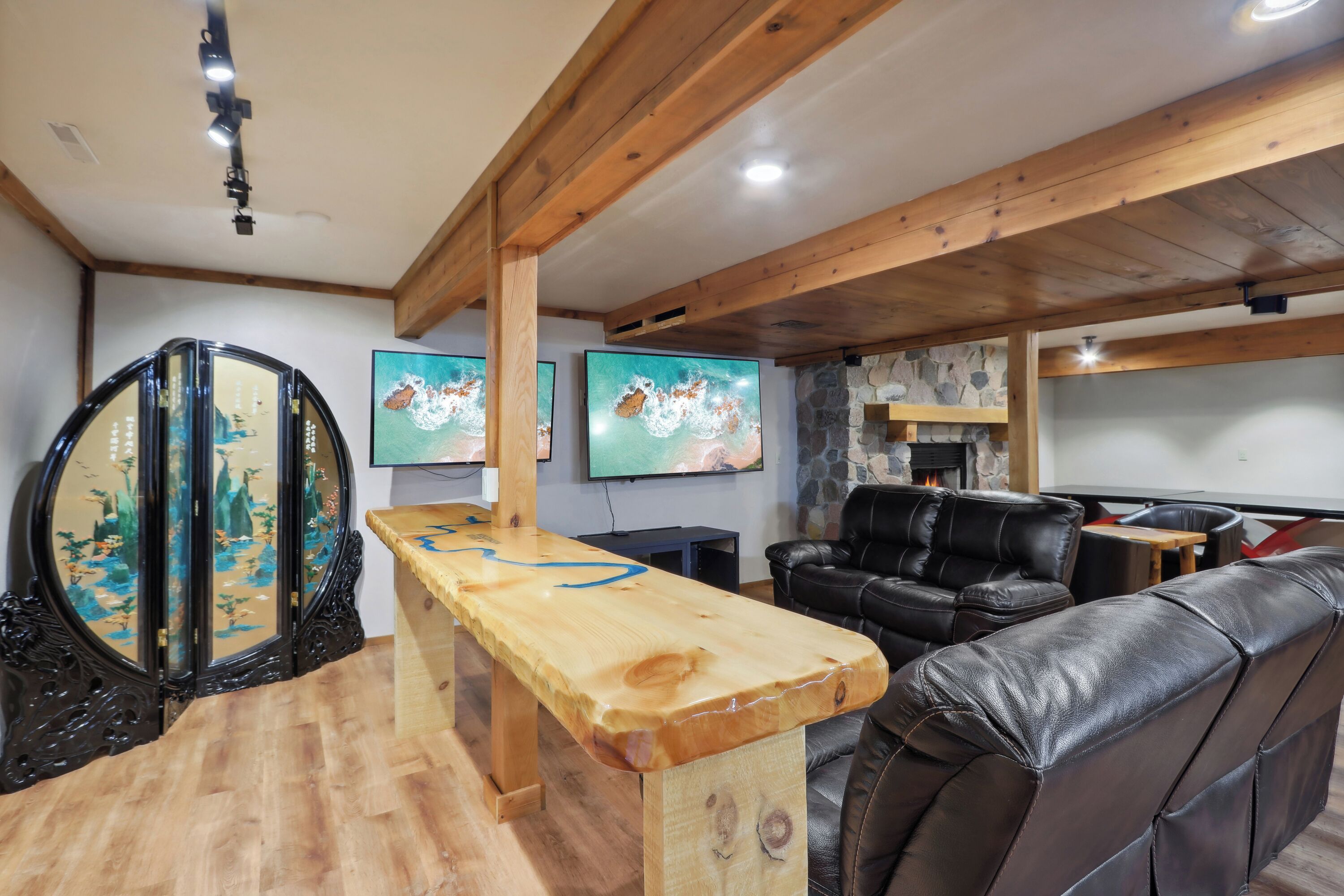 Ein Holztisch mit blauem Muster, ein schwarzes Leder Sofa und ein Kamin aus Stein.