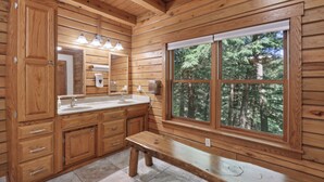 A wooden cabin interior with a large window, wooden cabinets, a sink, and a bench. - Charming 7-bedroom lodge with AC, WiFi in awesome Lake Delton Wisconsin Dells (Baraboo)