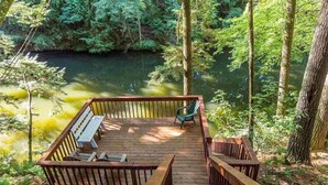 A wooden deck with benches and a view of a forested area and a river. - Charming 7-bedroom lodge with AC, WiFi in awesome Lake Delton Wisconsin Dells (Baraboo)