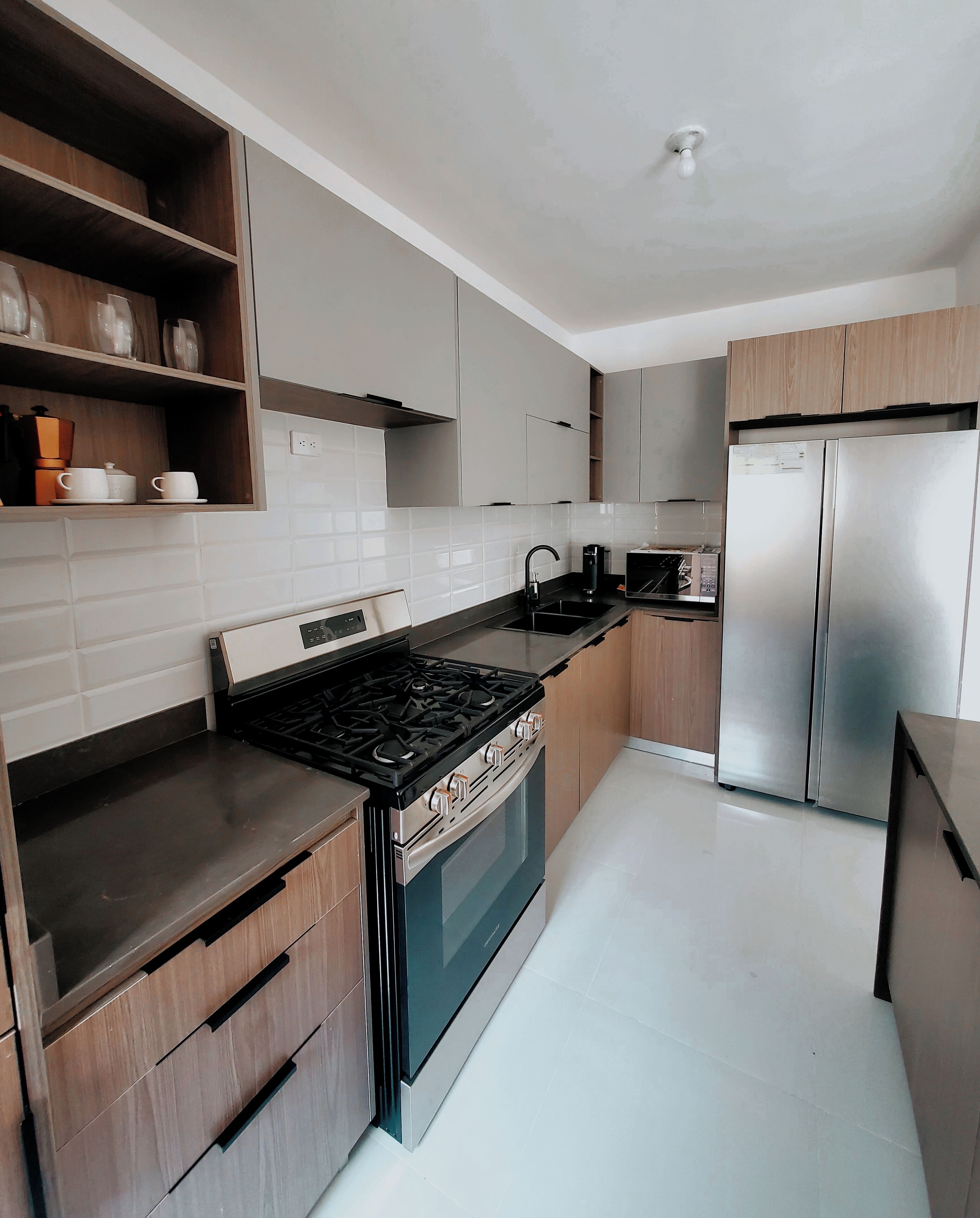 Una cocina moderna con estufa a gas, horno, refrigerador de acero inoxidable y armarios de madera.