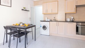 A compact kitchen with a washing machine, a coffee maker, and a dining area with chairs and a table. - 2-bedroom apartment - close to beaches and center (Torrevieja)
