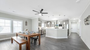Une cuisine moderne dotée d’un îlot central, d’appareils électroménagers en acier inoxydable et de luminaires suspendus.