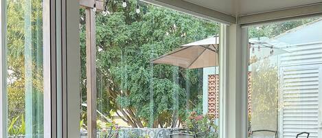 Ein modernes Wohnzimmer mit einem Ecksofa, großen Fenstern und einer Topfpflanze.