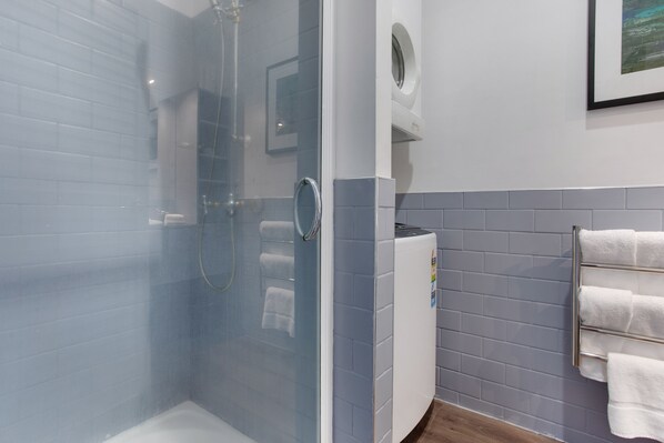 A modern bathroom with a glass-enclosed shower, a built-in toilet, and a wall-mounted towel rack.