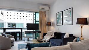 Una sala de estar moderna con un conjunto de sofás, un televisor de pantalla plana y un comedor con mesa y sillas.