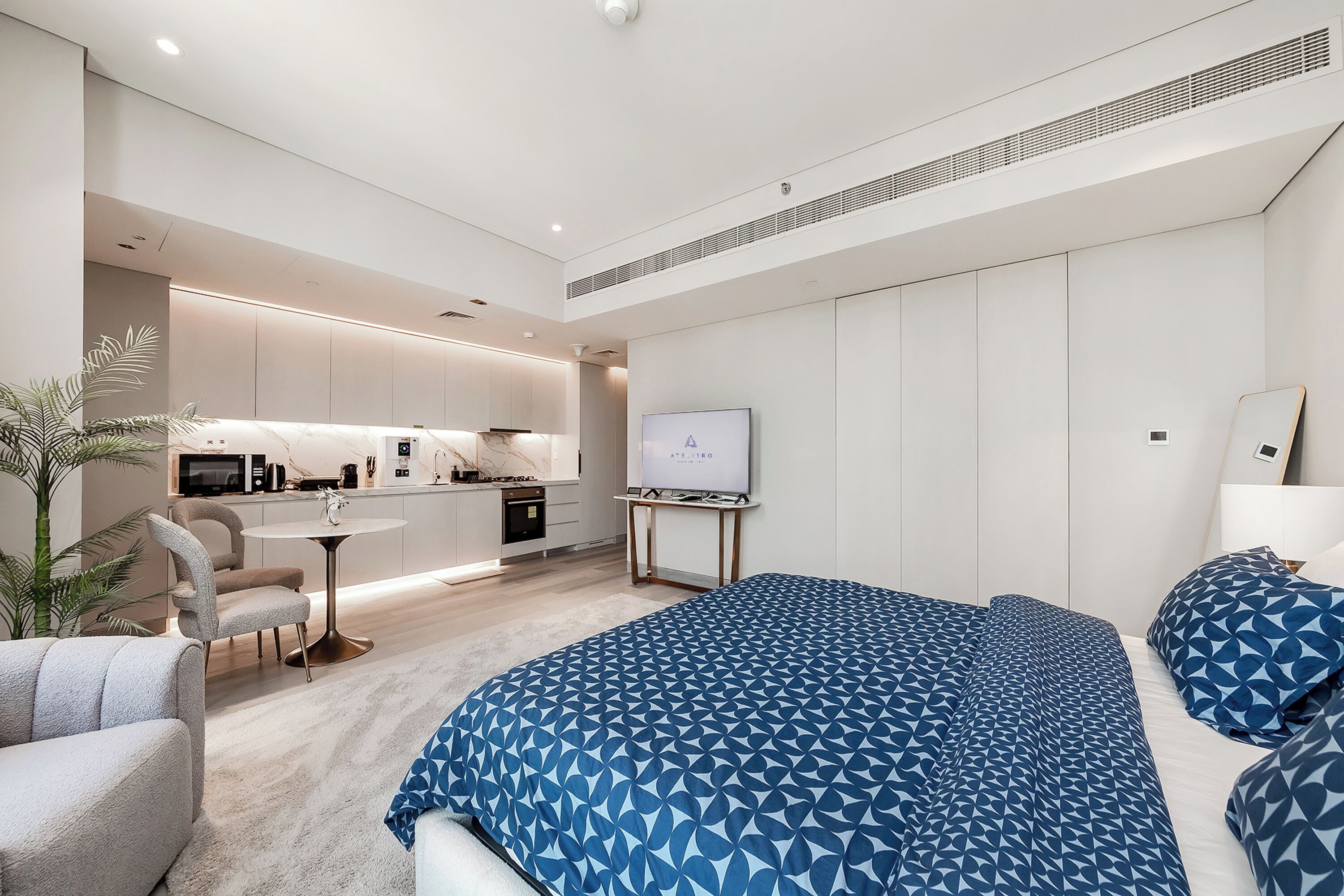 Una habitación de hotel moderna con una cama grande, un escritorio y una kitchenette.