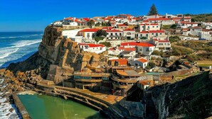 A coastal town with buildings on a cliff, a sea wall, and a small pool. - Charming Urban Apartment in Porto's Heart (Porto)
