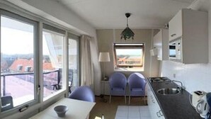 A compact hotel room with a balcony, a kitchenette, and a view of the cityscape. - Apartment With Dunes View of Petten (Petten)